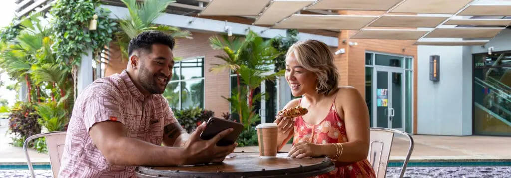 young couple talking and drinking coffee while looking at tablet