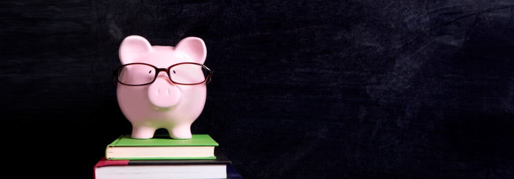 piggy bank with glasses on top of a pile of books