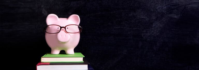 piggy bank with glasses on top of a pile of books